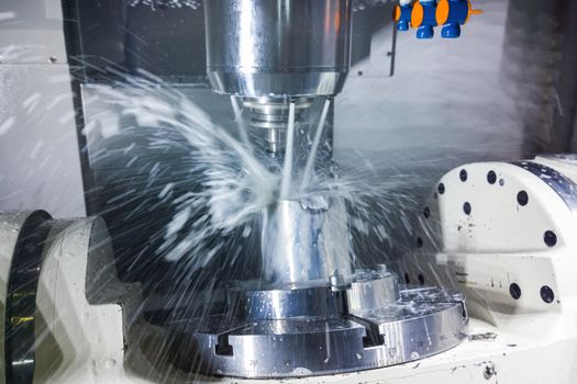 5-axis cnc milling machine at work with coolant under pressure. Table-table type of machine's kinematics. Natural motion blur of coolant streams and real capture technique.