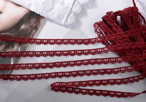 Tapes of red vinous gentle guipure, beauty silk lace fabric on light background. Elastic material. Using for Atelier and needlework store. Flat lay style