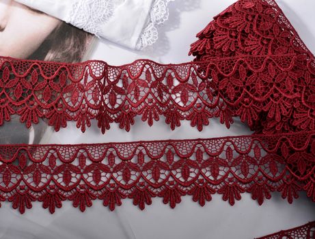 Tapes of red vinous gentle guipure, beauty silk lace fabric on light background. Elastic material. Using for Atelier and needlework store. Flat lay style