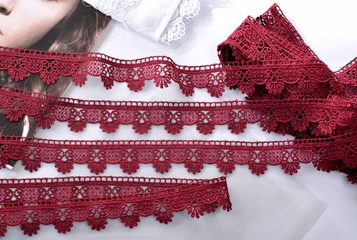 Tapes of red vinous gentle guipure, beauty silk lace fabric on light background. Elastic material. Using for Atelier and needlework store. Flat lay style