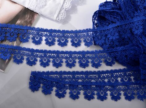 Tapes of blue gentle guipure, beauty silk lace fabric on light background. Elastic material. Using for Atelier and needlework store. Flat lay style