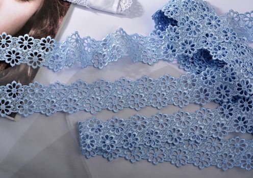 Tapes of blue gentle guipure, beauty silk lace fabric on light background. Elastic material. Using for Atelier and needlework store. Flat lay style