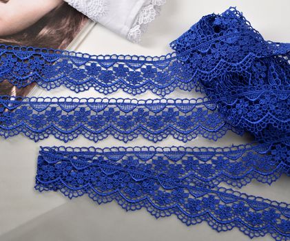Tapes of blue gentle guipure, beauty silk lace fabric on light background. Elastic material. Using for Atelier and needlework store. Flat lay style