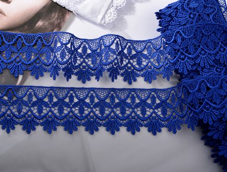 Tapes of blue gentle guipure, beauty silk lace fabric on light background. Elastic material. Using for Atelier and needlework store. Flat lay style