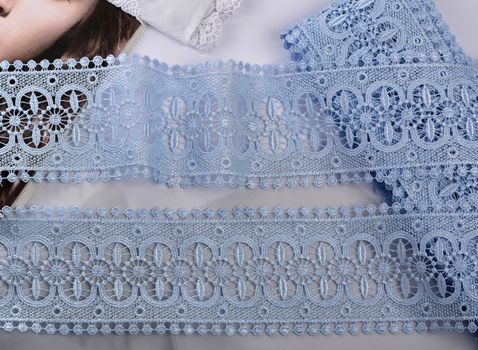 Tapes of blue gentle guipure, beauty silk lace fabric on light background. Elastic material. Using for Atelier and needlework store. Flat lay style