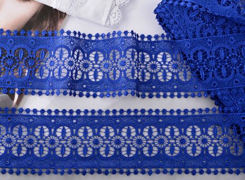 Tapes of blue gentle guipure, beauty silk lace fabric on light background. Elastic material. Using for Atelier and needlework store. Flat lay style