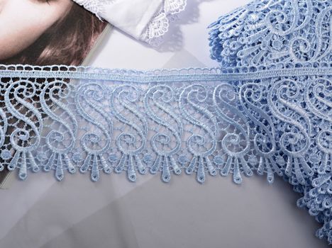 Tapes of blue gentle guipure, beauty silk lace fabric on light background. Elastic material. Using for Atelier and needlework store. Flat lay style