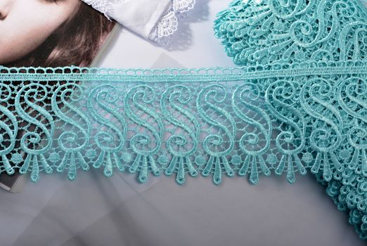 Tapes of blue gentle guipure, beauty silk lace fabric on light background. Elastic material. Using for Atelier and needlework store. Flat lay style