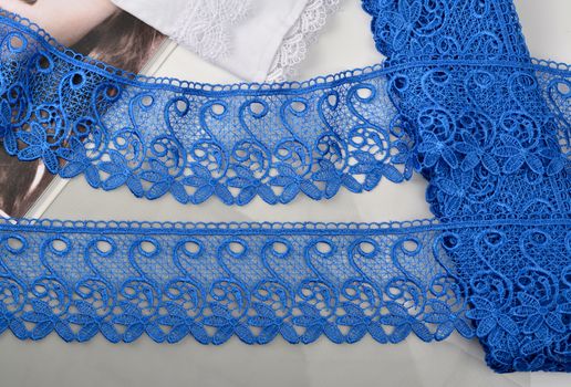 Tapes of blue gentle guipure, beauty silk lace fabric on light background. Elastic material. Using for Atelier and needlework store. Flat lay style