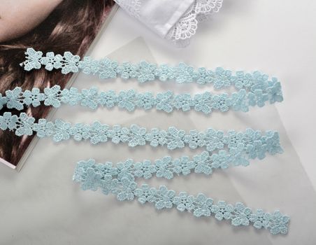Tapes of blue gentle guipure, beauty silk lace fabric on light background. Elastic material. Using for Atelier and needlework store. Flat lay style