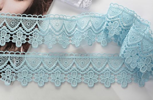 Tapes of blue gentle guipure, beauty silk lace fabric on light background. Elastic material. Using for Atelier and needlework store. Flat lay style