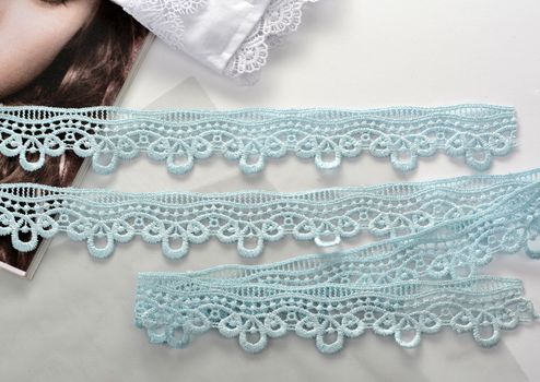 Tapes of blue gentle guipure, beauty silk lace fabric on light background. Elastic material. Using for Atelier and needlework store. Flat lay style