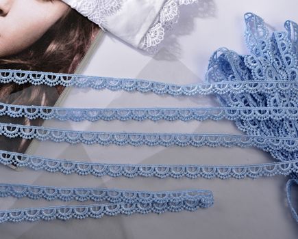 Tapes of blue gentle guipure, beauty silk lace fabric on light background. Elastic material. Using for Atelier and needlework store. Flat lay style