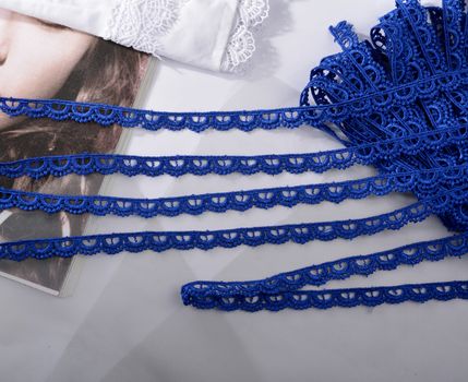 Tapes of blue gentle guipure, beauty silk lace fabric on light background. Elastic material. Using for Atelier and needlework store. Flat lay style