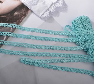 Tapes of blue gentle guipure, beauty silk lace fabric on light background. Elastic material. Using for Atelier and needlework store. Flat lay style