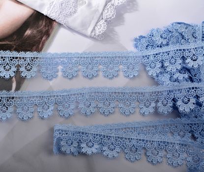 Tapes of blue gentle guipure, beauty silk lace fabric on light background. Elastic material. Using for Atelier and needlework store. Flat lay style