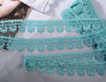 Tapes of blue gentle guipure, beauty silk lace fabric on light background. Elastic material. Using for Atelier and needlework store. Flat lay style