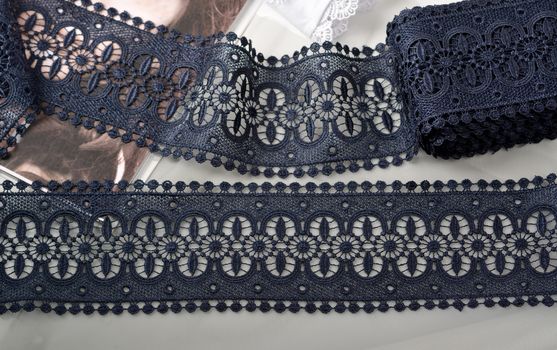Tapes of blue gentle guipure, beauty silk lace fabric on light background. Elastic material. Using for Atelier and needlework store. Flat lay style