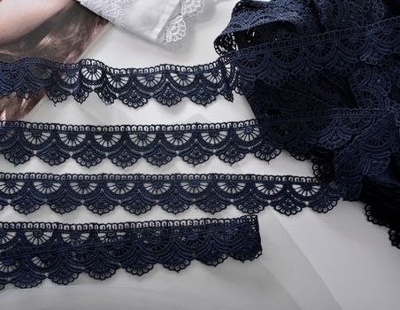 Tapes of blue gentle guipure, beauty silk lace fabric on light background. Elastic material. Using for Atelier and needlework store. Flat lay style