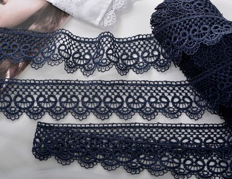 Tapes of blue gentle guipure, beauty silk lace fabric on light background. Elastic material. Using for Atelier and needlework store. Flat lay style