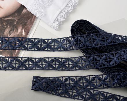 Tapes of blue gentle guipure, beauty silk lace fabric on light background. Elastic material. Using for Atelier and needlework store. Flat lay style