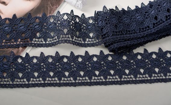 Tapes of blue gentle guipure, beauty silk lace fabric on light background. Elastic material. Using for Atelier and needlework store. Flat lay style