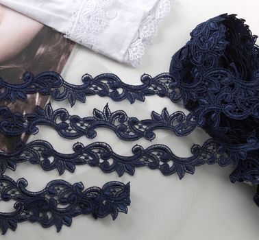 Tapes of blue gentle guipure, beauty silk lace fabric on light background. Elastic material. Using for Atelier and needlework store. Flat lay style
