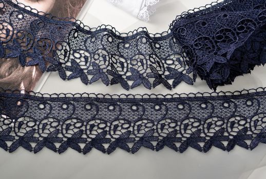 Tapes of blue gentle guipure, beauty silk lace fabric on light background. Elastic material. Using for Atelier and needlework store. Flat lay style