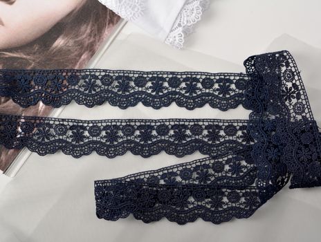 Tapes of blue gentle guipure, beauty silk lace fabric on light background. Elastic material. Using for Atelier and needlework store. Flat lay style
