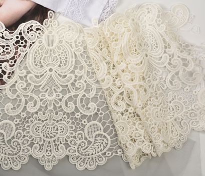 Tapes of ecru white guipure, beauty silk lace fabric on light background. Elastic material. Using for Atelier and needlework store. Flat lay style