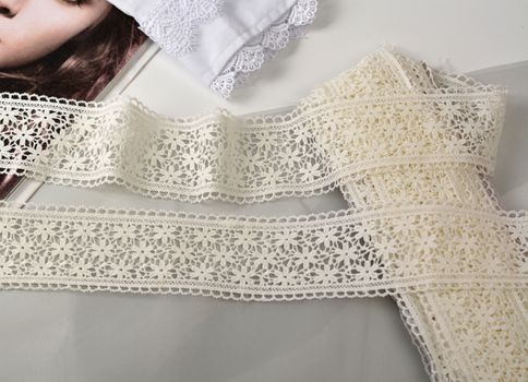 Tapes of ecru white guipure, beauty silk lace fabric on light background. Elastic material. Using for Atelier and needlework store. Flat lay style