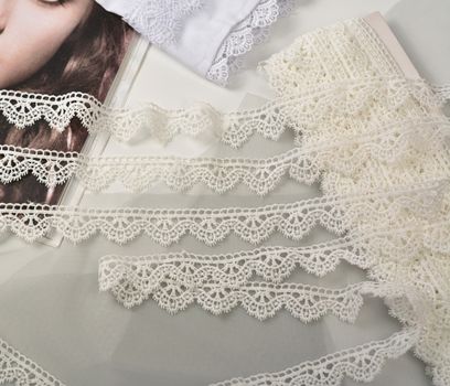 Tapes of ecru white guipure, beauty silk lace fabric on light background. Elastic material. Using for Atelier and needlework store. Flat lay style