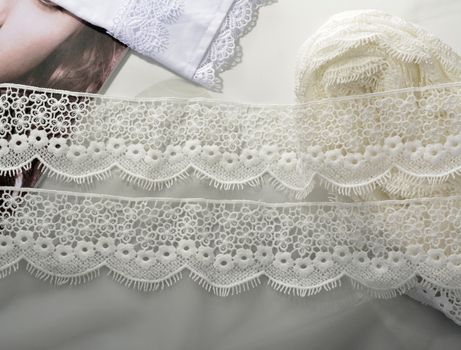 Tapes of ecru white guipure, beauty silk lace fabric on light background. Elastic material. Using for Atelier and needlework store. Flat lay style