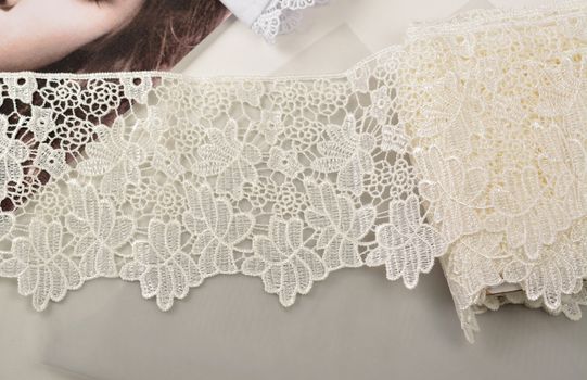 Tapes of ecru white guipure, beauty silk lace fabric on light background. Elastic material. Using for Atelier and needlework store. Flat lay style
