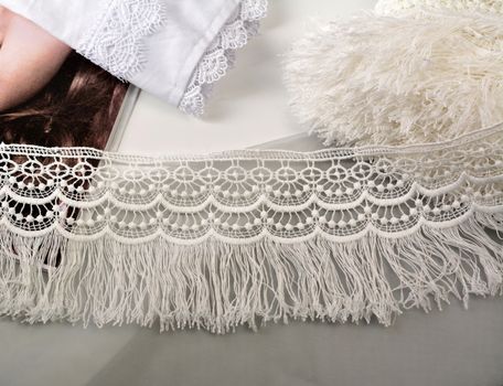 Tapes of ecru white guipure, beauty silk lace fabric on light background. Elastic material. Using for Atelier and needlework store. Flat lay style