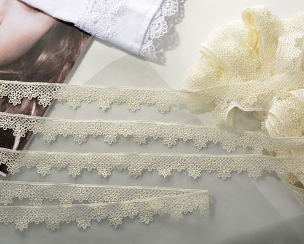 Tapes of ecru white guipure, beauty silk lace fabric on light background. Elastic material. Using for Atelier and needlework store. Flat lay style