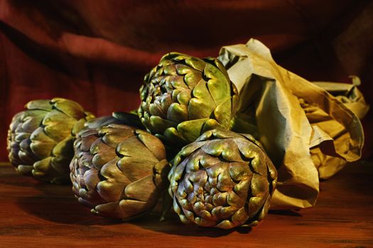 Bunch of artichoke on red wooden table , the background is colored ,