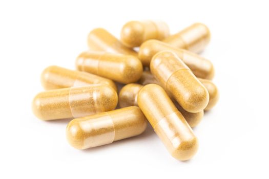 pile of orange organic capsules isolated on white background closeup with selective focus.
