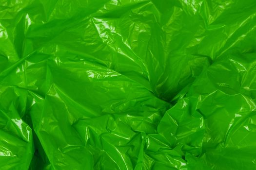 crumpled green polyethilene film abstract background with selective focus.