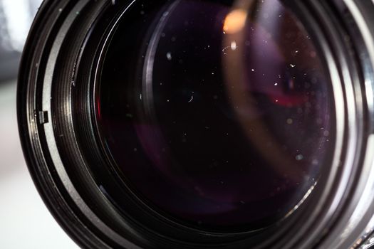 Dust particles in camera lens closeup shot with selective focus and blur. Large front element of professional objective.