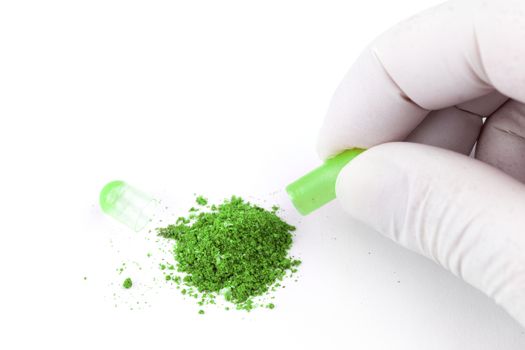 hand in medical glove opening ufo green color organic med capsule isolated on white background closeup.
