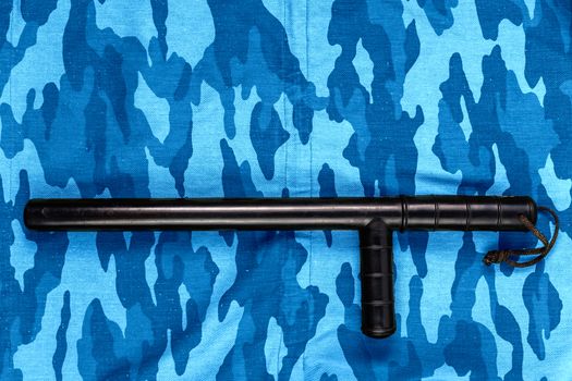 black rubber baton on blue urban russian riot police camouflage flat lay top-down perspective.