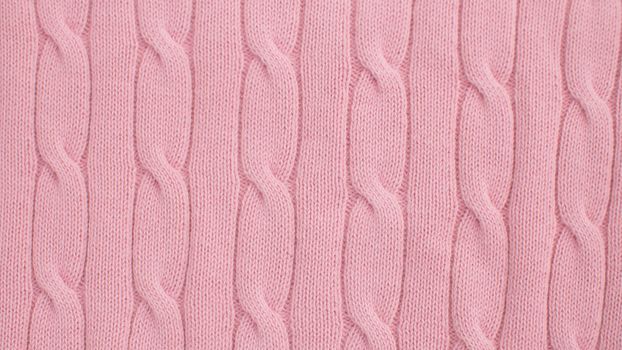 Extreme close up pink wool knitted fabric with scythe pattern. Texture, textile background. Macro shooting