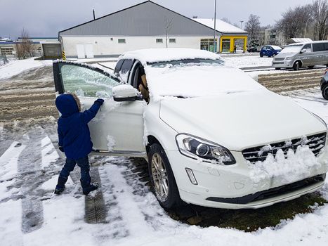 Child frees car from snow and ice Leherheide, Bremerhaven in Germany.