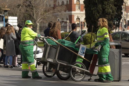 Madrid, Spain - February 2, 2020: Two workers of the public cleaning service, in their daily cleaning tasks, in the morning, in the streets of Madrid, near Atocha.