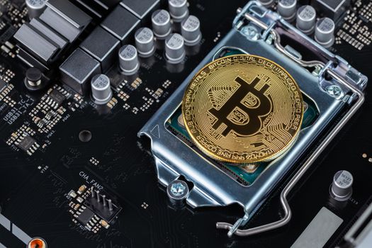 cryptocurrency background - bitcoin physical shiner in cpu socket of modern motherboard with selective focu and blur