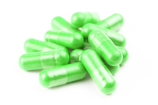 pile of ufo green organic capsules isolated on white background closeup with selective focus.