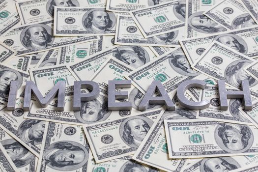 The word IMPEACH laid with aluminium letters on the US dollar banknotes background - with selective focus and diagonal composition.