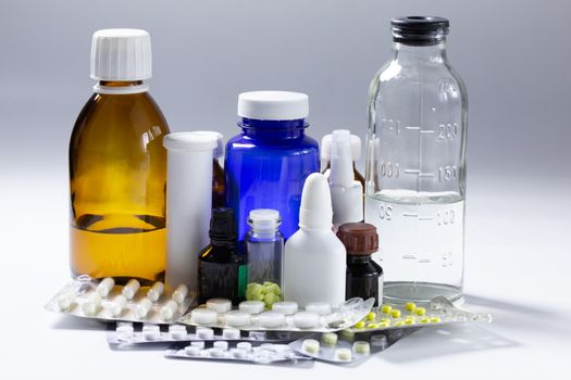 bunch of used medial bottles and tablets on gray background.