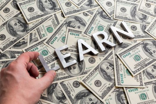 learn to earn - concept made of aluminium characters laid on us monay background
